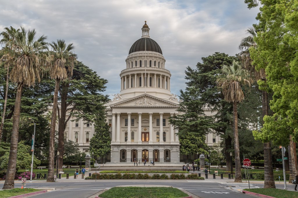 The domed California State Capitol building seen down a tree-lined Capitol Mall
