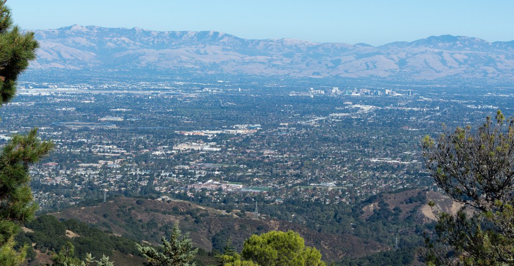 A wide view of the Santa Clara Valley floor with buildings stretching toward hills under a clear sky