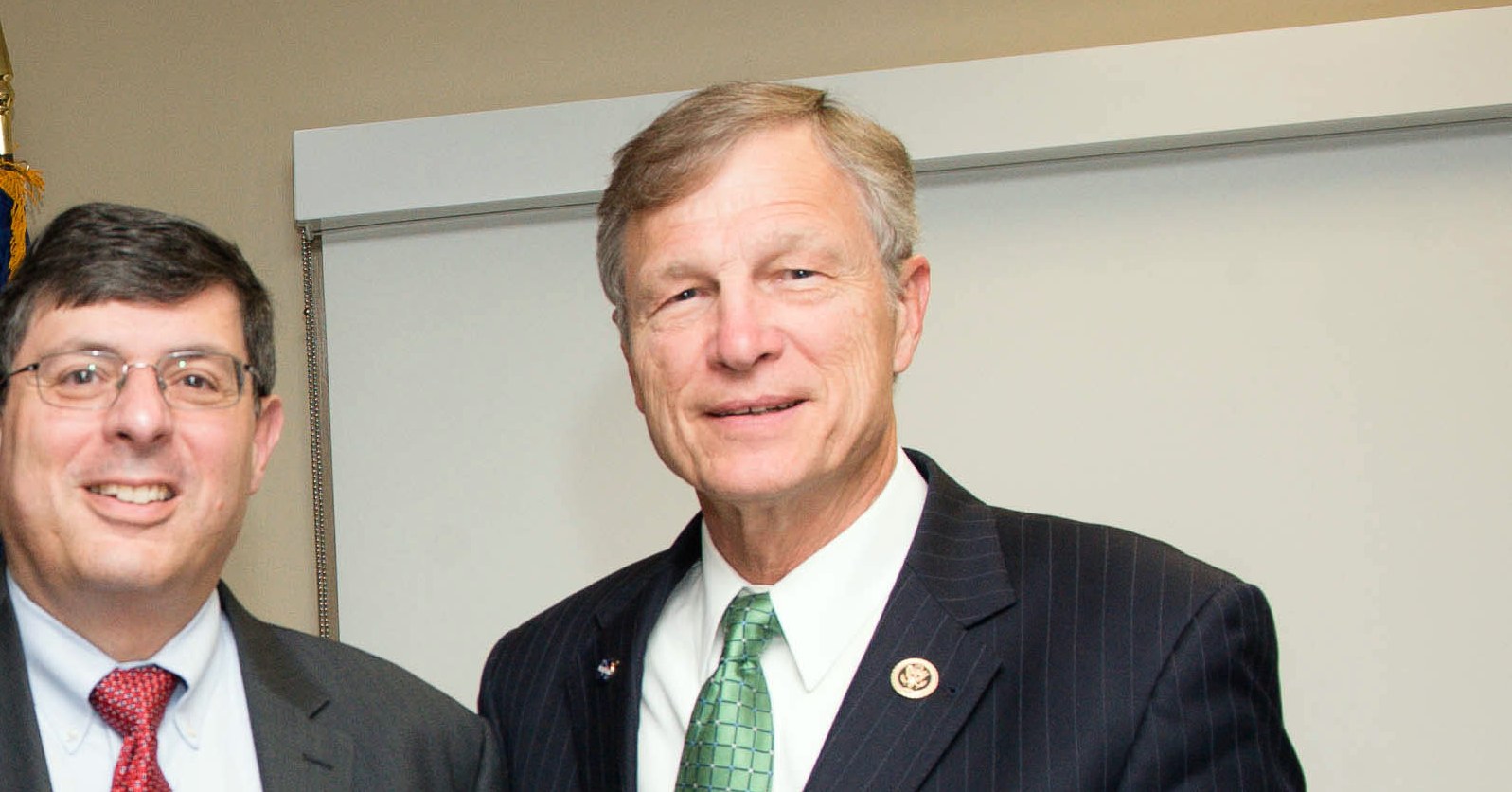 Rep. Brian Babin, in a dark suit and green tie, smiles while posing for a photo at NASA's Goddard Space Flight Center.