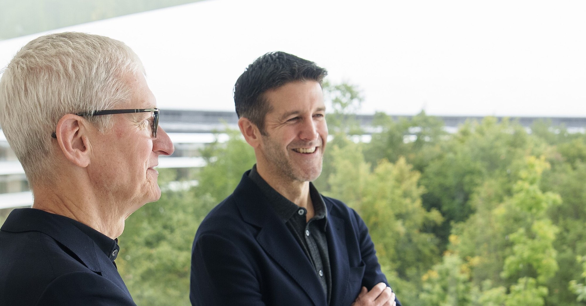 Apple's John Ternus, smiling with arms crossed, stands beside Tim Cook during a May 2026 meeting with European Parliament President Roberta Metsola.