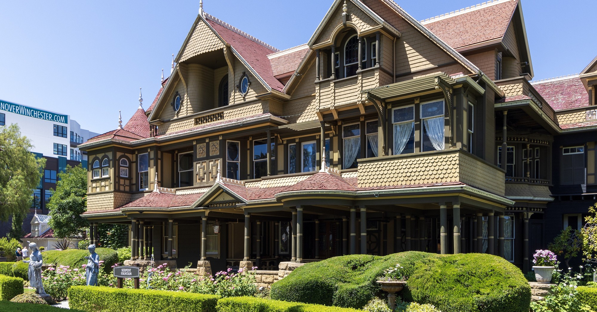 The ornate Victorian facade of the Winchester Mystery House in San Jose, with turrets, red roofs and manicured hedges